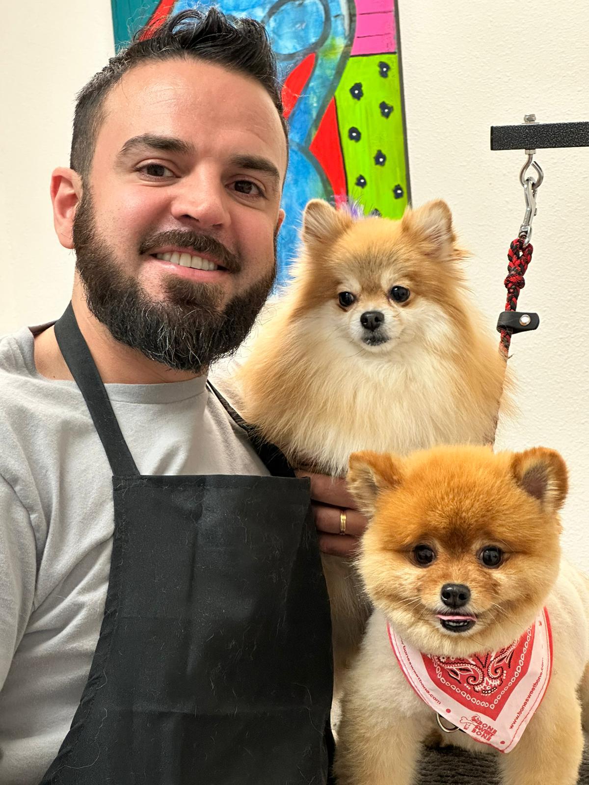 Male pet groomer smiling with two pomeranian dogs after a mobile grooming session in Los Angeles, California.