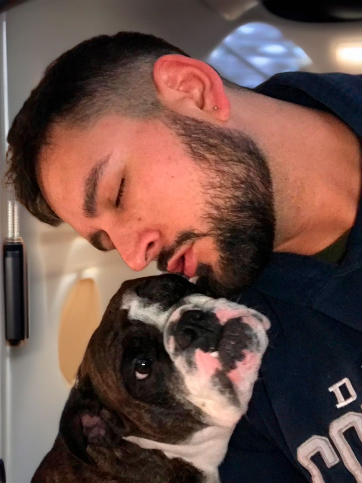 Male pet groomer showing affection to a bulldog inside a mobile pet spa in Austin, Texas.